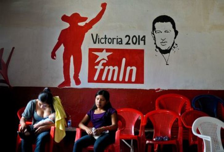 Dos mujeres aguardan su turno para votar ante un mural del FMLN que hace referencia a Hugo Chávez. (Jose CABEZAS/AFP)