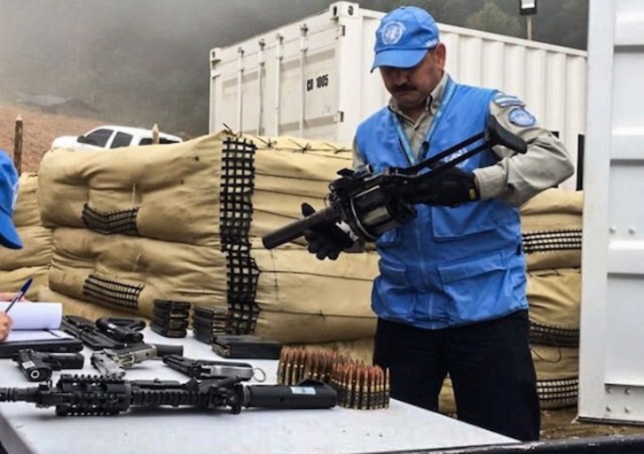 Un miembro de la Misión de la ONU inspecciona armamento entregado por las FARC en la localidad colombiana de Buenos Aires. (Daniel SANDOVAL/AFP PHOTO)