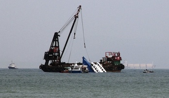 Uno de los barcos accidentados es sacado del agua por una grua. (Laurent FIEVET/AFP)