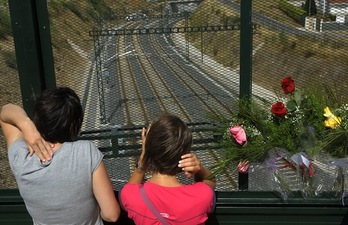 Dos mujeres observan el lugar del accidente junto a una ofrenda floral. (Miguel RIOPA/AFP) 