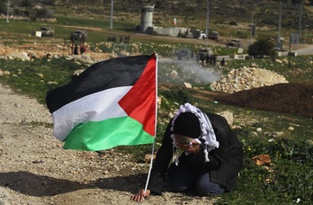Mujer palestina se protege de gases lanzados por las fuerzas israelís. (Abbas MOMANI / AFP)