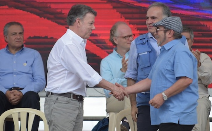 El comandante guerrillero ‘Timochenko’ y el presidente Juan Manuel Santos se saludan en el acto que oficializa el desarme de las FARC-EP. (Raúl ARBOLEDA/AFP)